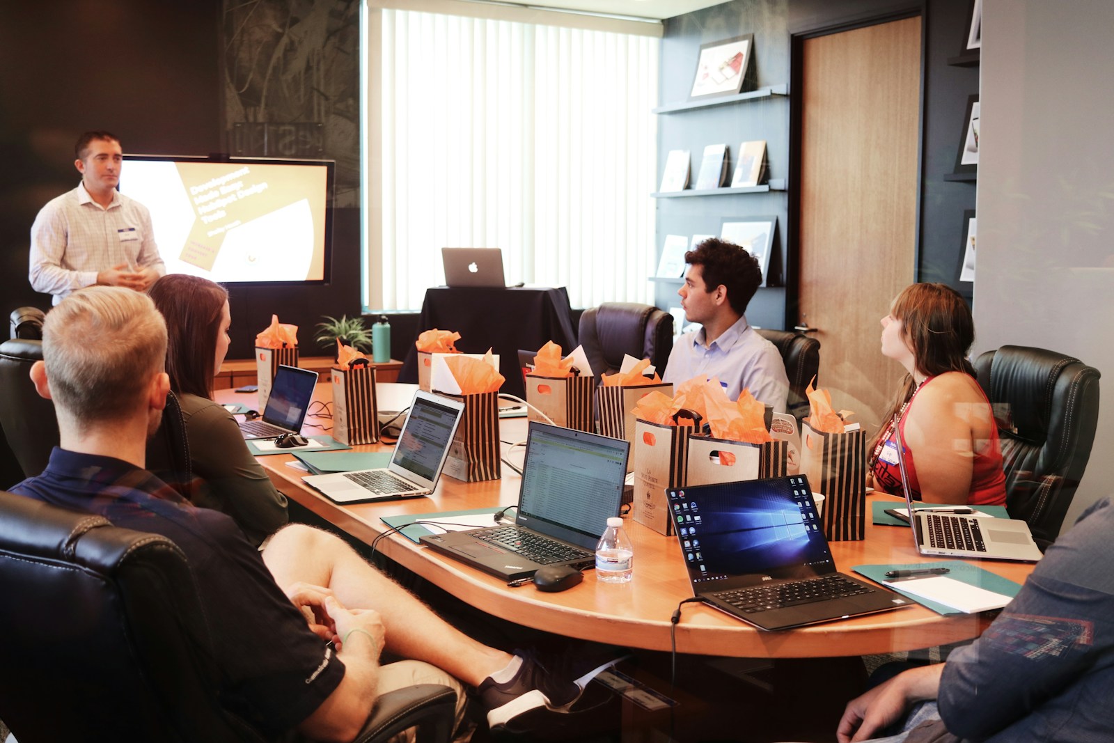 man standing in front of people sitting beside table with laptop computers, general liability